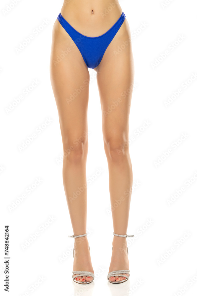 front view of female legs and hips with blue bikini panties and high heels sandals on white background