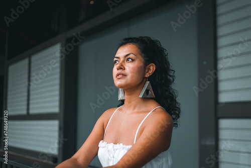 Colombian woman in stylish white dress, striking a pose in a chic interior setting © Daniel