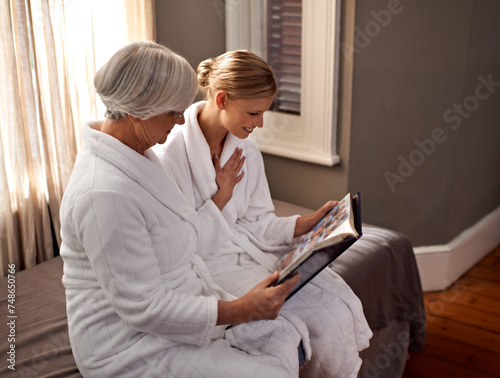 Grandmother, woman and spa day at home, hotel and happy for bonding and looking at photo album memories. Senior lady, daughter and moment for self care, robe and bedroom for comfort and hospitality
