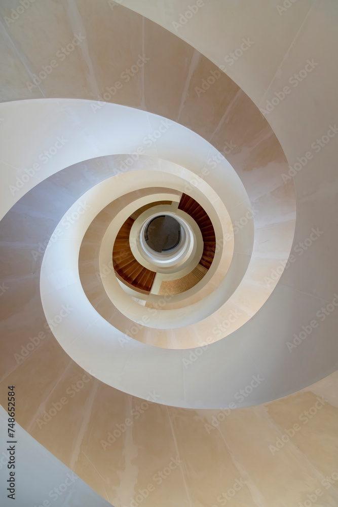 Fototapeta premium Birds eye view of a modern helix or circular staircase in white and beige colors with view from top to bottom