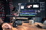 Photographe vidéaste devant un ordinateur en train de faire du montage et de la post-production dans un studio créatif