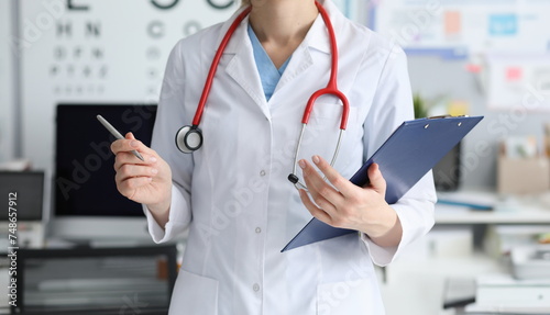 Female doctor is standing office holding folder. Surgical and therapeutic hospital. Laboratory and instrumental diagnostics. Round-the-clock medical care without mandatory hospitalization