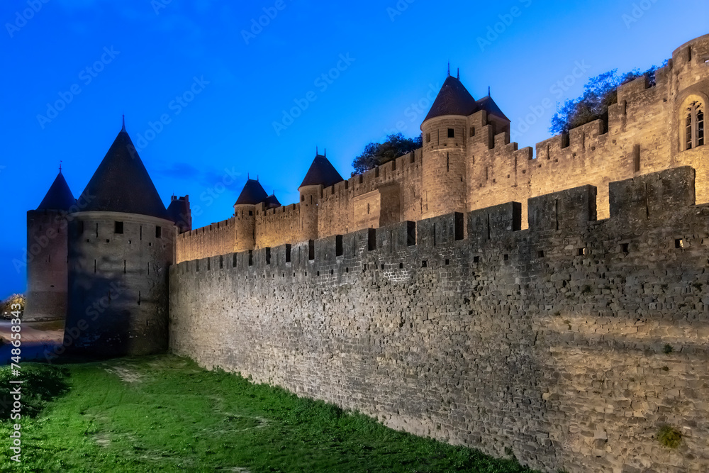 Night view over length of fortified wall with battlement and towers of the city of Carcassonne, a medieval fortress from Gallo-Roman period and part of UNESCO list of World Heritage Sites