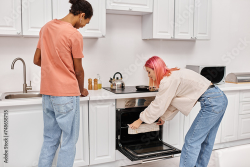 good looking jolly interracial couple in cozy homewear cooking together in kitchen at home