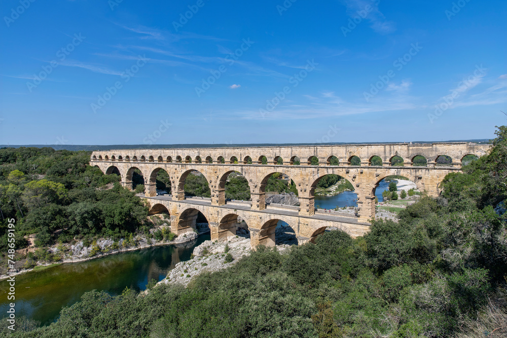 High angle view of the aqueduct bridge Pont du Gard over the Gardon river near Vers-Pont-du-Gard, France with well-preserved arched tiers, built by 1st-century Romans