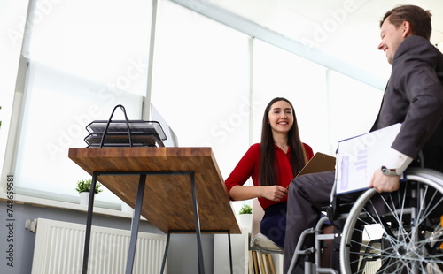 Portrait of cheerful smiling company manager interviewing candidate on vacancy. Disabled man sitting in wheelchair. Adaptation of people with disabilities in society concept