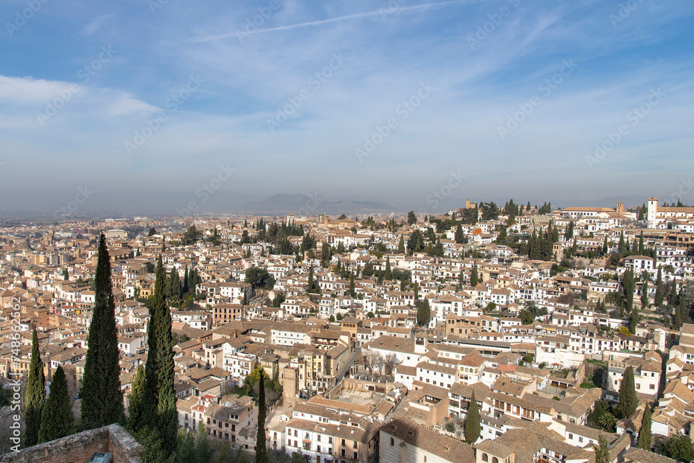 High level panoramic view over the city of Granada, Spain seen from the Alhambra palace with on far-right Mirador de San Nicolás square known for dramatic sunset views and Sierra Nevada in background