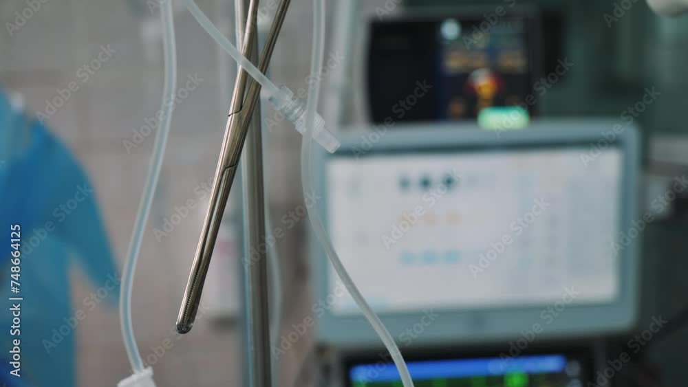 Close-up of surgical scissors or clamp against the background of a heart monitor during a surgical operation in the clinic. Resuscitation in the hospital. Close-up of surgical scissors or clamp against the background of a heart monitor during a surgical operation in the clinic. Resuscitation in the hospital.
