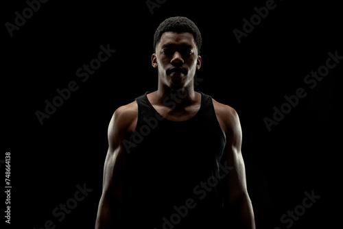 Basketball player against black background. Serious concentrated african american man silhouette.