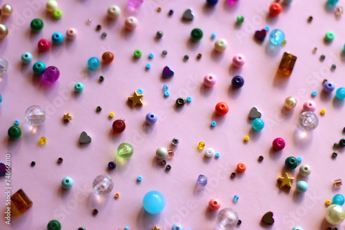 Various colorful beads on bright pink background. Selective focus.