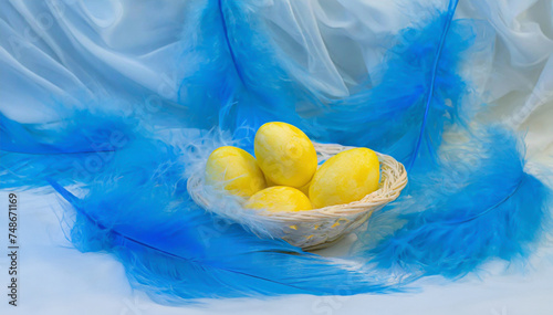Wielkanocne tło świąteczne, żółte pisanki i niebieskie piórka