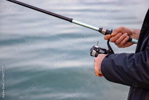 Fisherman holding a fishing rod on the background of the sea