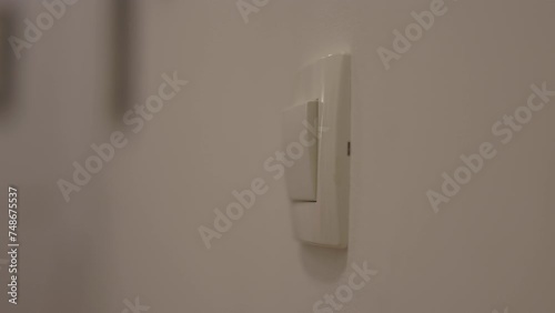 Close up of woman left hand turning on light switch in the apartment 