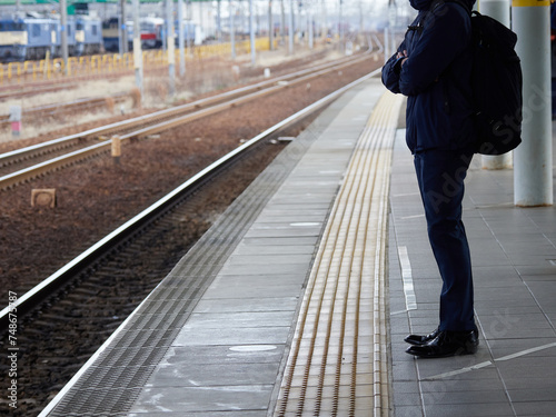 冬の駅で電車待ちの若い男性サラリーマンの姿