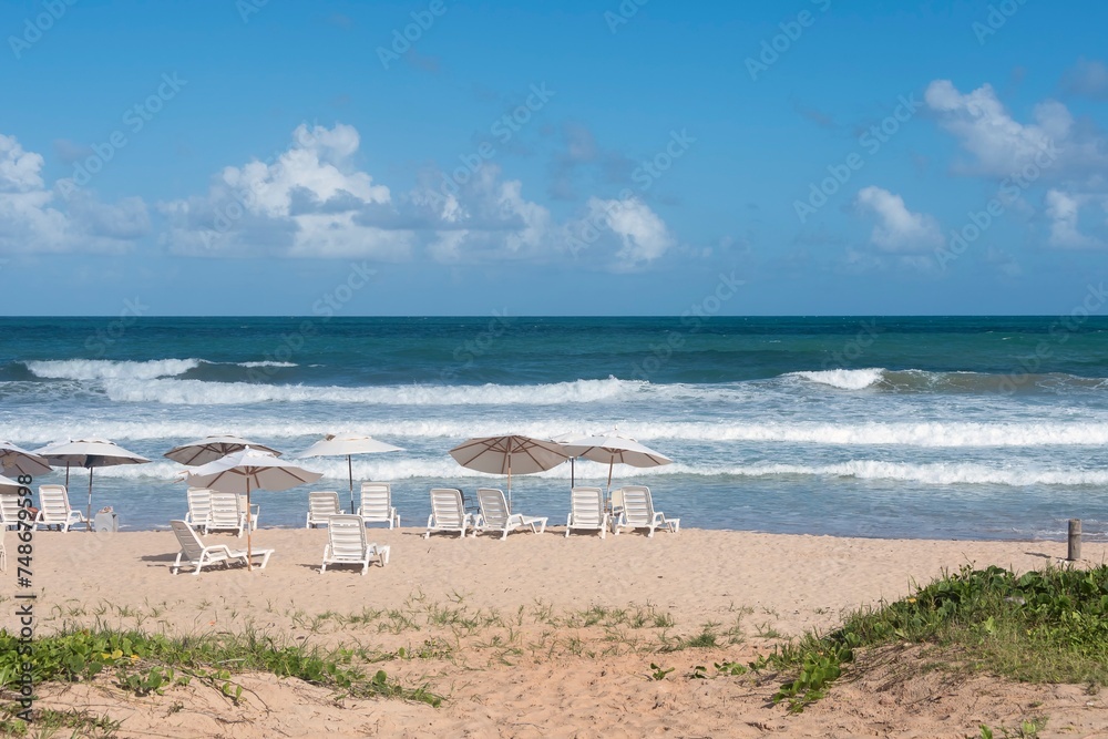 Porto de Galinhas Beach, Pernambuco, Brazil. Chairs and umbrellas on the sand, blue and turquoise sea, horizon and blue sky. Porto de Galinhas Beach, Pernambuco, Brazil. Chairs and umbrellas on the sand, blue and turquoise sea, horizon and blue sky.