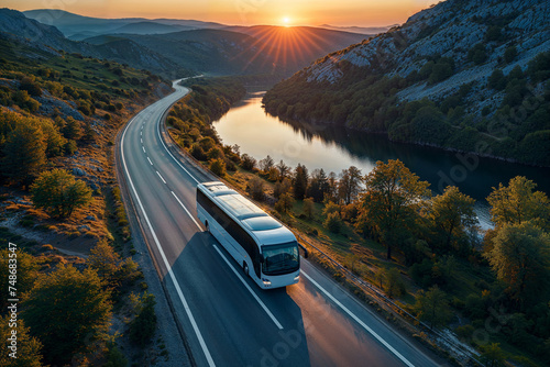  Aerial view of a white intercity bus traveling on a scenic highway at sunset