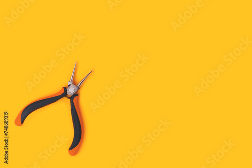 Round-nose pliers on a yellow background. Copy space for text.