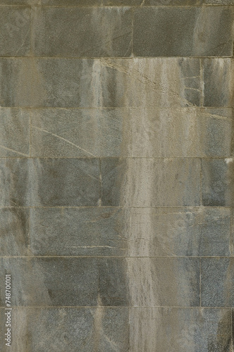 The texture of a wall of large granite tiles that are covered with white streaks when exposed to dampness.