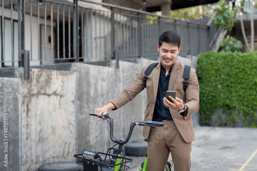 Asian businessman in a suit is riding a bicycle on the city streets for his morning commute to work. Eco transportation concept, sustainable lifestyle concept