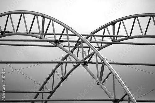 Tableau sur toile Black and white architectural image of two arching metal industrial supports appearing to intersect to make an interesting and appealing artistic image