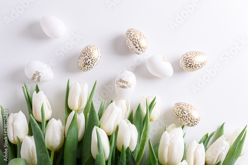 Floral border from bouquet of white tulips, Easter eggs and toys on white background. Easter celebration concept. Copy space. Top view