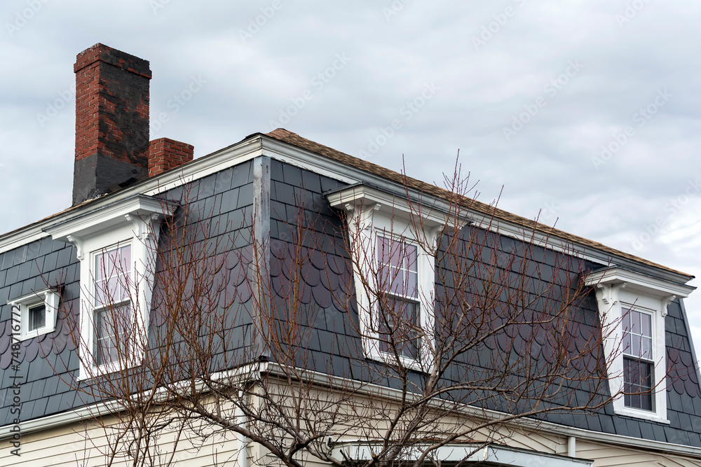 Mansard roof and dormers of a family house in Brighton on a winter day, MA, USA