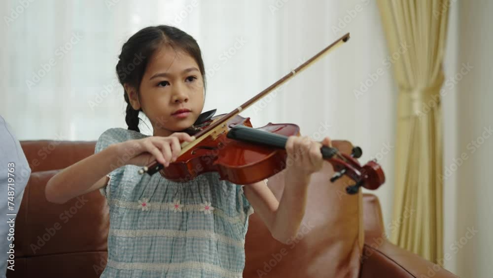 Handheld locked shot, lovely girl playing violin, Happily Grandfather and granddaughter enjoy to playing music instrument with guitar and violin together in living room Handheld locked shot, lovely girl playing violin, Happily Grandfather and granddaughter enjoy to playing music instrument with guitar and violin together in living room