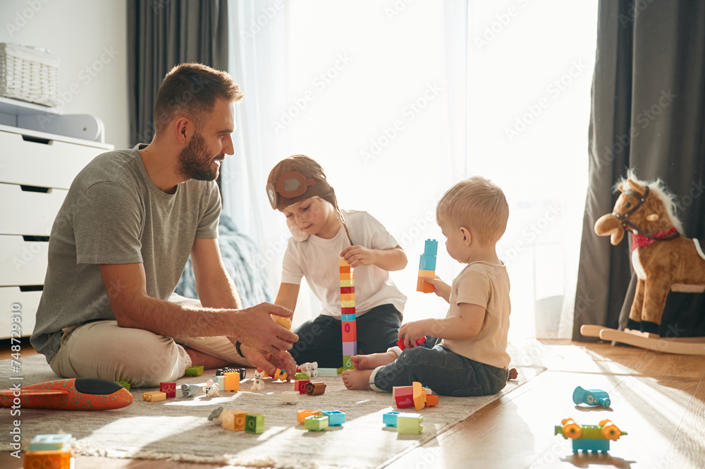 Construction toys. Father is playing with two little boys on the floor Construction toys. Father is playing with two little boys on the floor