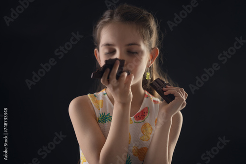 Beautiful little girl eating dark chocolate cocoa bar 