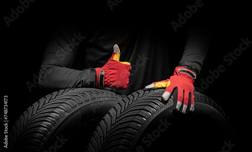 Car tire service and hands of mechanic holding new tyre on black background with copy space for text.