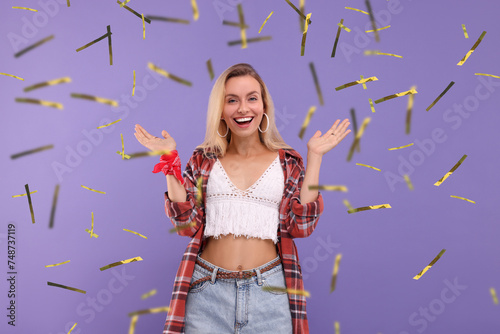 Happy woman and flying confetti on violet background