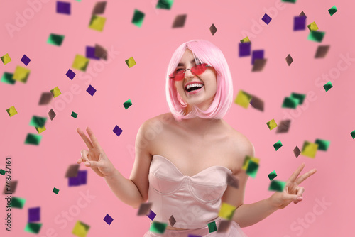 Happy woman and flying confetti on pink background