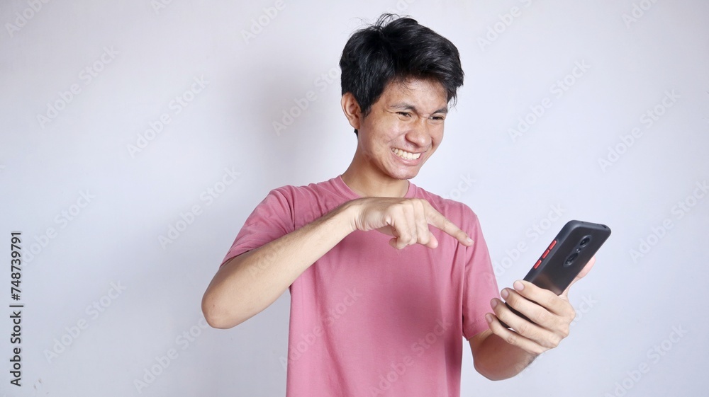 Excited and annoyed Asian man with smartphone holding pointing gesture Excited and annoyed Asian man with smartphone holding pointing gesture