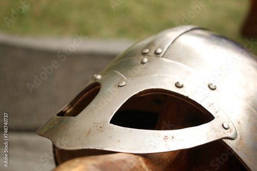 Closeup of a silver colored, shiny metal historically inspired Nordic Viking combat helmet belonging to a medieval reenactor.