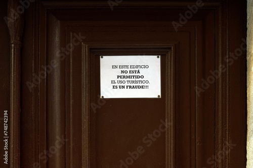 Image of a warning sign stuck on a brown door indicating the prohibition of tourist use of the building, calling it a fraud. Translation: Tourist use is not allowed in this building, it is a fraud