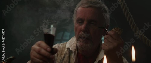 An old pirate eats and drinks inside ship cabin