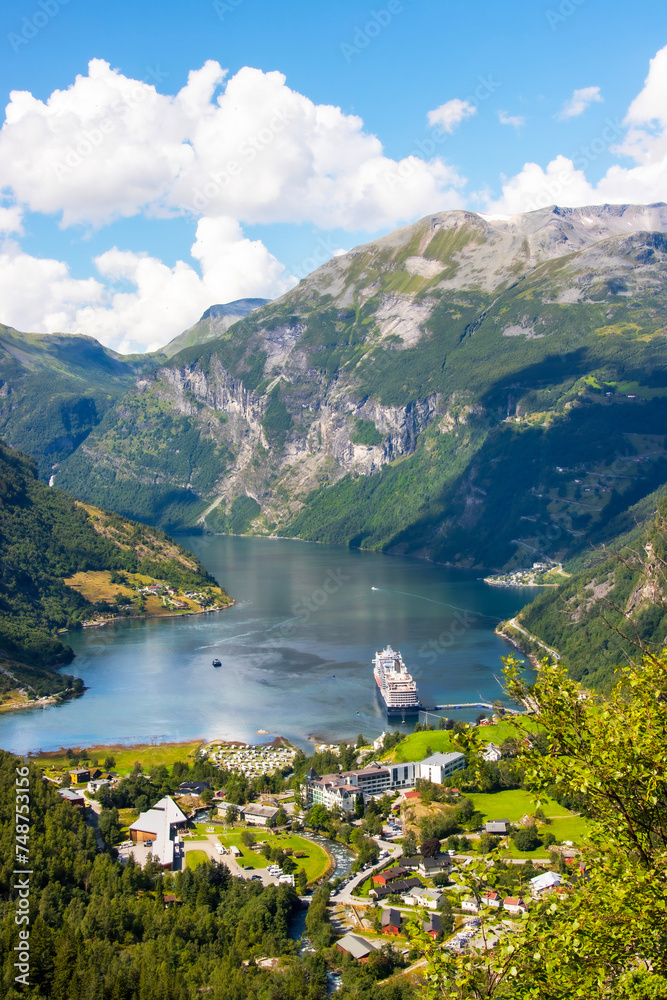 Portrait view across the town of Geiranger and the Fjord with a cruise ship 