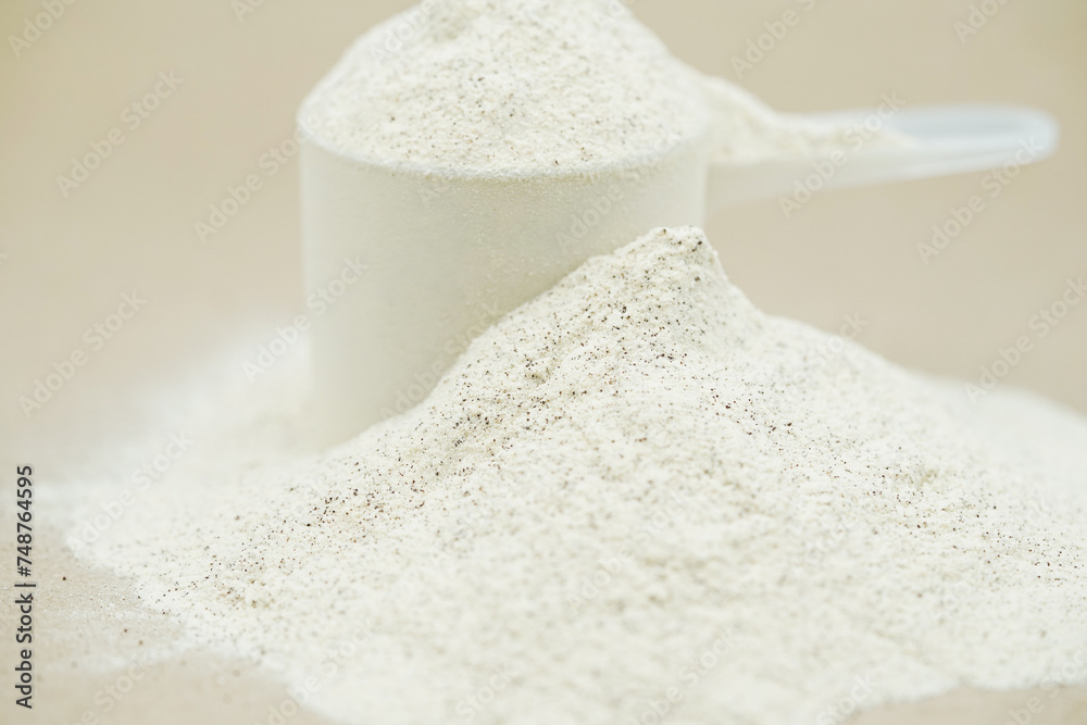 Close up of plant protein powder in plastic scoop. Whey protein powder background.