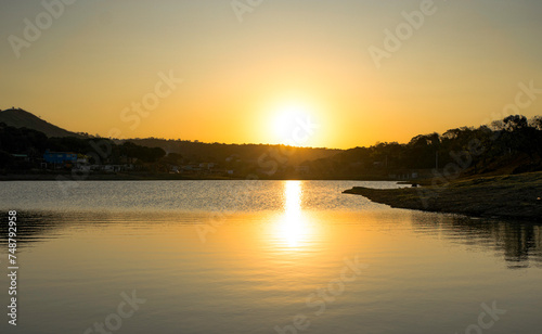 Sunset at dusk with clear skies, with reflection in a lake in the Jardim das Oliveiras neighborhood, Esmeraldas, Minas Gerais, Brazil.