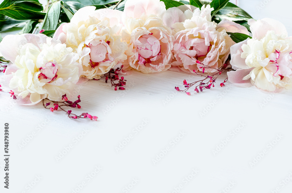 Delicate light peonies in a wreath on a white wooden background for wallpaper, template, invitation, background.