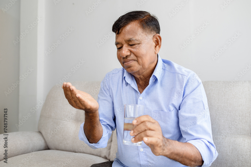 Senior Asian man taking pill and drinking water.