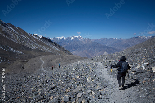 Trekkers on trail with mountains at background.