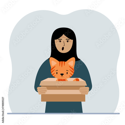 A woman is holding a cardboard box with a beautiful ginger cat. The concept of rescue, help and care for pets.