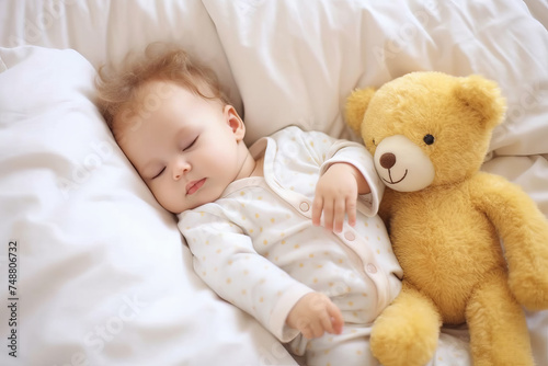 A cute newborn baby sleeping on bed with a teddy bear
