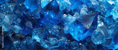 A collection of blue glass chips stacked on a wooden table, creating a vibrant contrast. The chips vary in size and shape, reflecting light.