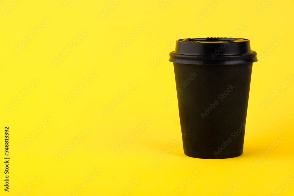 Eco black paper cup, coffee paper cup on yellow background. Mockup for your advertisement. Copy space. Eco black paper cup, coffee paper cup on yellow background. Mockup for your advertisement. Copy space.