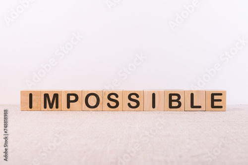 IMPOSSIBLE word concept written on wooden cubes lying on a light table and light background.