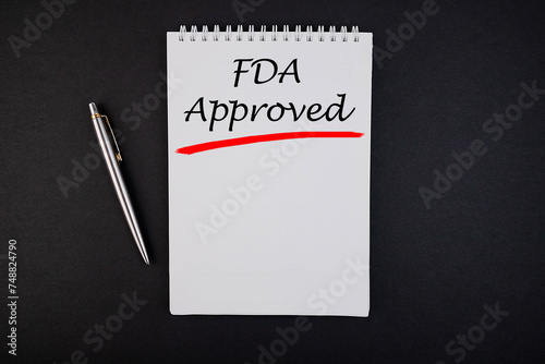 FDA Approved text, inscription, phrase is written in a notebook that lies on a dark table and a pen. Business concept.