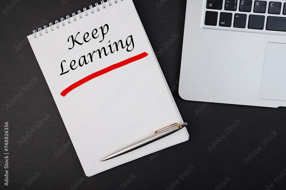 The text, the inscription, the phrase Keep Learning is written in a notebook that lies on a dark table with a laptop and pen. Business concept. The text, the inscription, the phrase Keep Learning is written in a notebook that lies on a dark table with a laptop and pen. Business concept.
