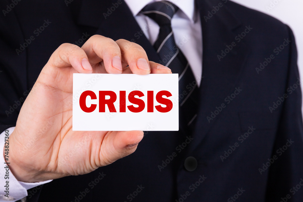 Businessman holding a card with word CRISIS